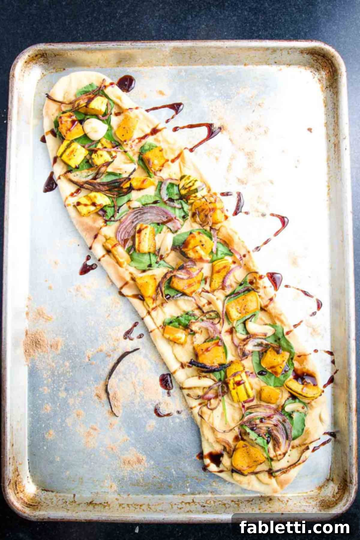 Effortless Plant-Based Flatbread 16 Flatbread pizza spread with hummus, topped with spinach, roasted squash and drizzled with date syrup.