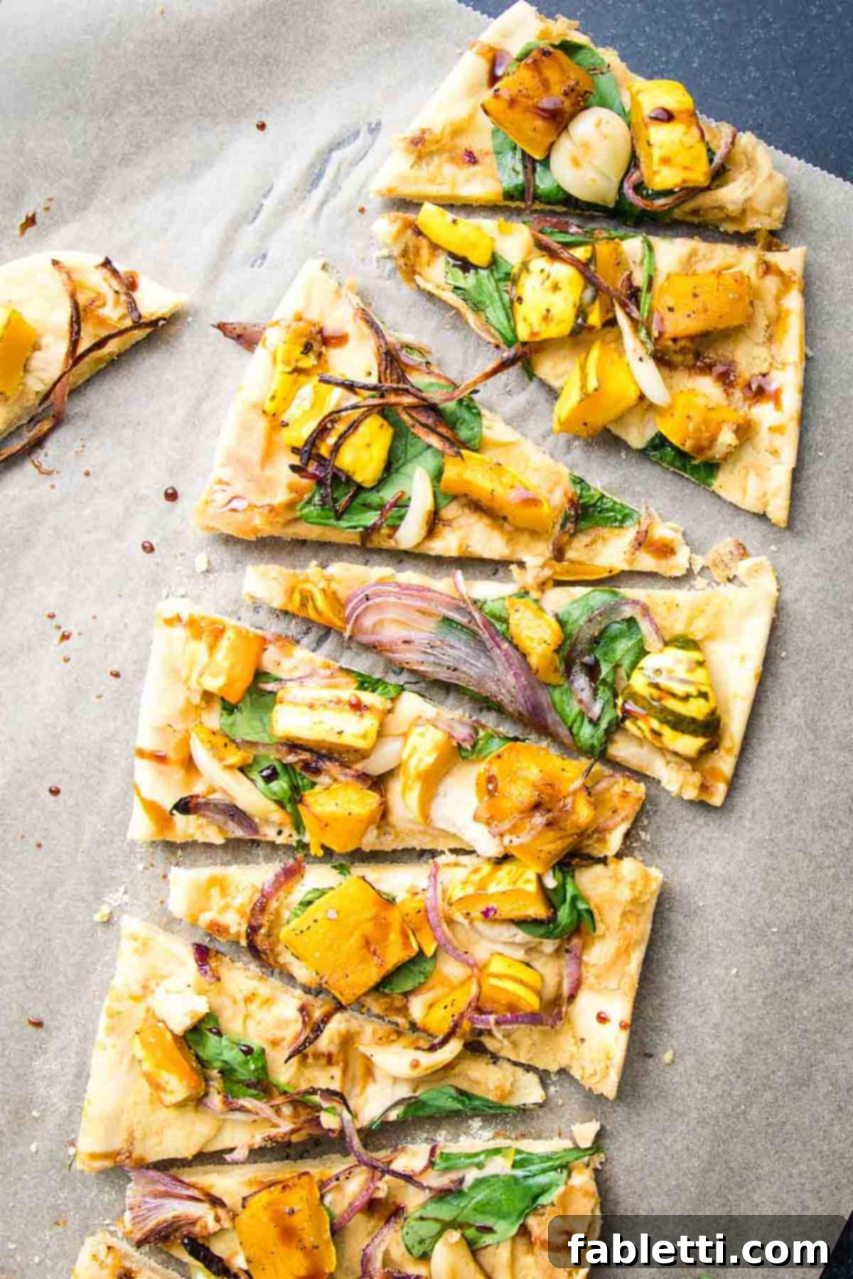 Effortless Plant-Based Flatbread 17 Flatbread pizza with roasted squash, onions and garlic cut into small triangle pieces.