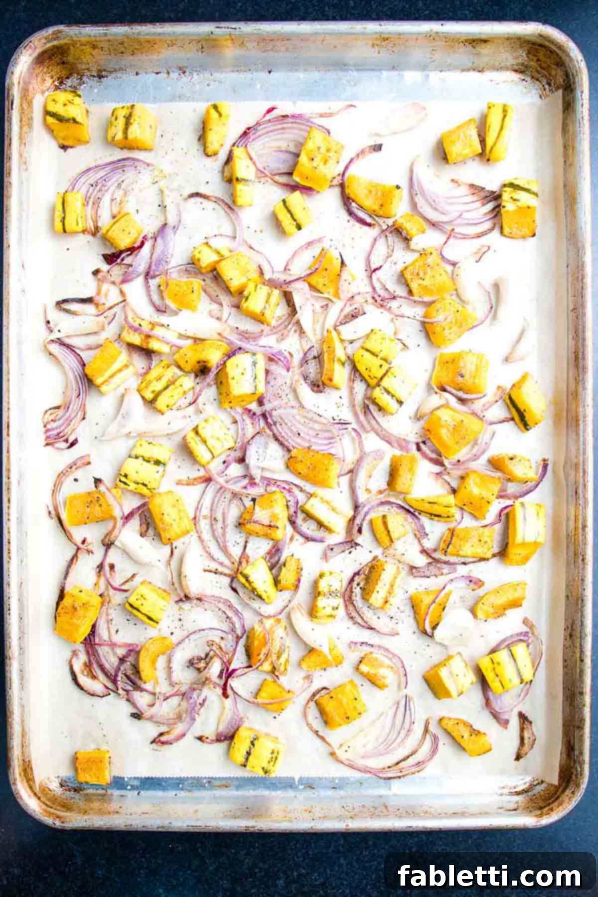 Effortless Plant-Based Flatbread 22 Baking sheet with roasted cubes of squash, thinly sliced onions and cloves or garlic.