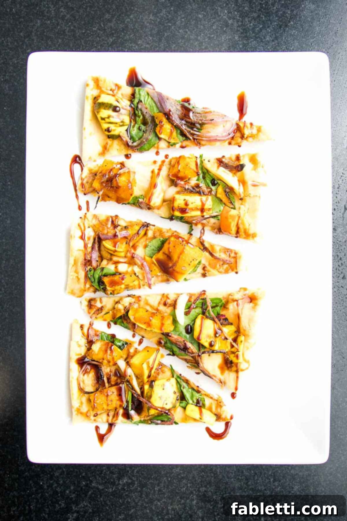 Effortless Plant-Based Flatbread 23 Slices of flatbread that are topped with hummus, roasted veggies and drizzled with date syrup.