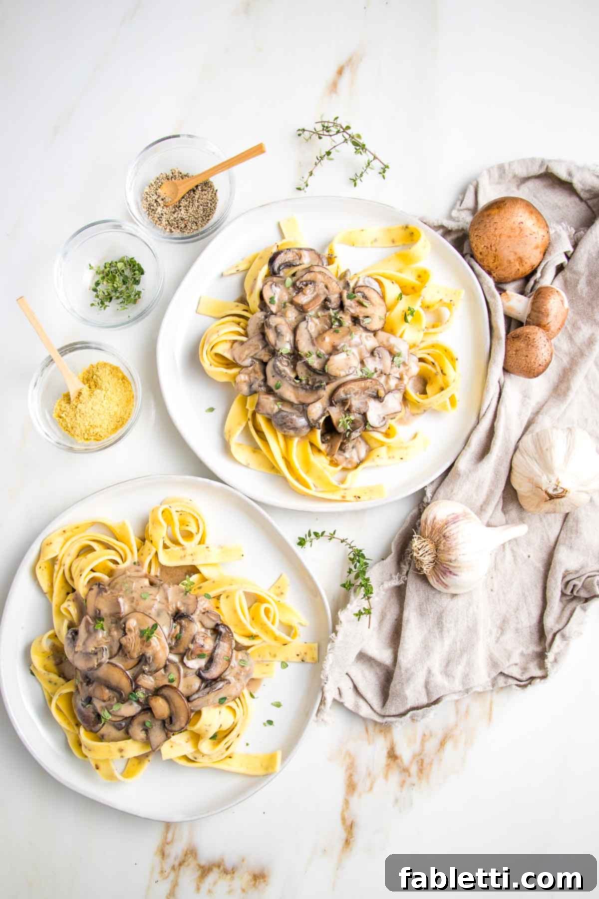 Hearty Vegan Mushroom Stroganoff 2 Two plates of ribbon noodles topped with creamy vegan mushroom stroganoff, garnished with fresh herbs.