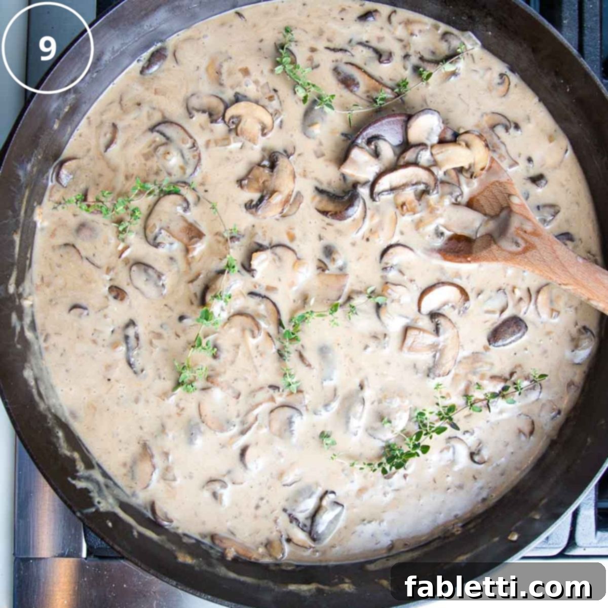 Hearty Vegan Mushroom Stroganoff 13 Fresh herbs being sprinkled over the finished creamy vegan mushroom stroganoff in a cast iron skillet, ready for serving.