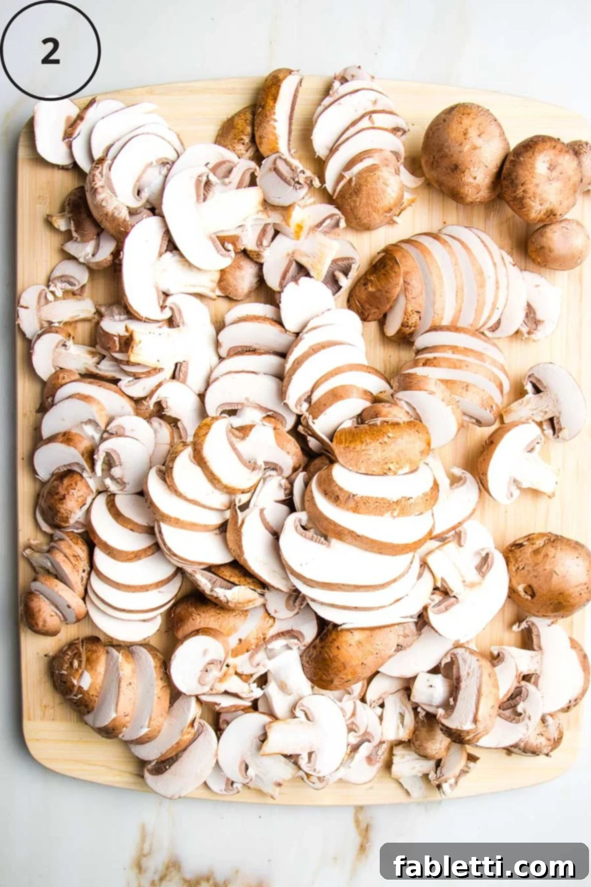 Hearty Vegan Mushroom Stroganoff 6 Thinly sliced portobello mushrooms on a rustic wooden cutting board, ready for the skillet.