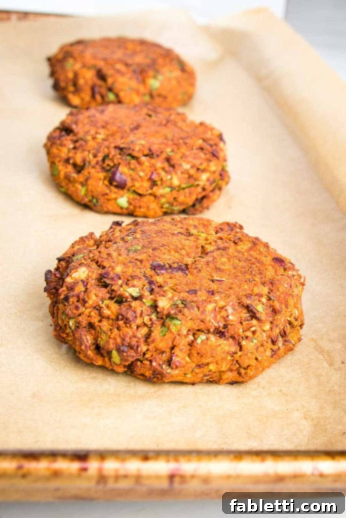 Neatly arranged quinoa veggie burger patties on a baking sheet lined with parchment paper, perfectly spaced and ready to be cooked.