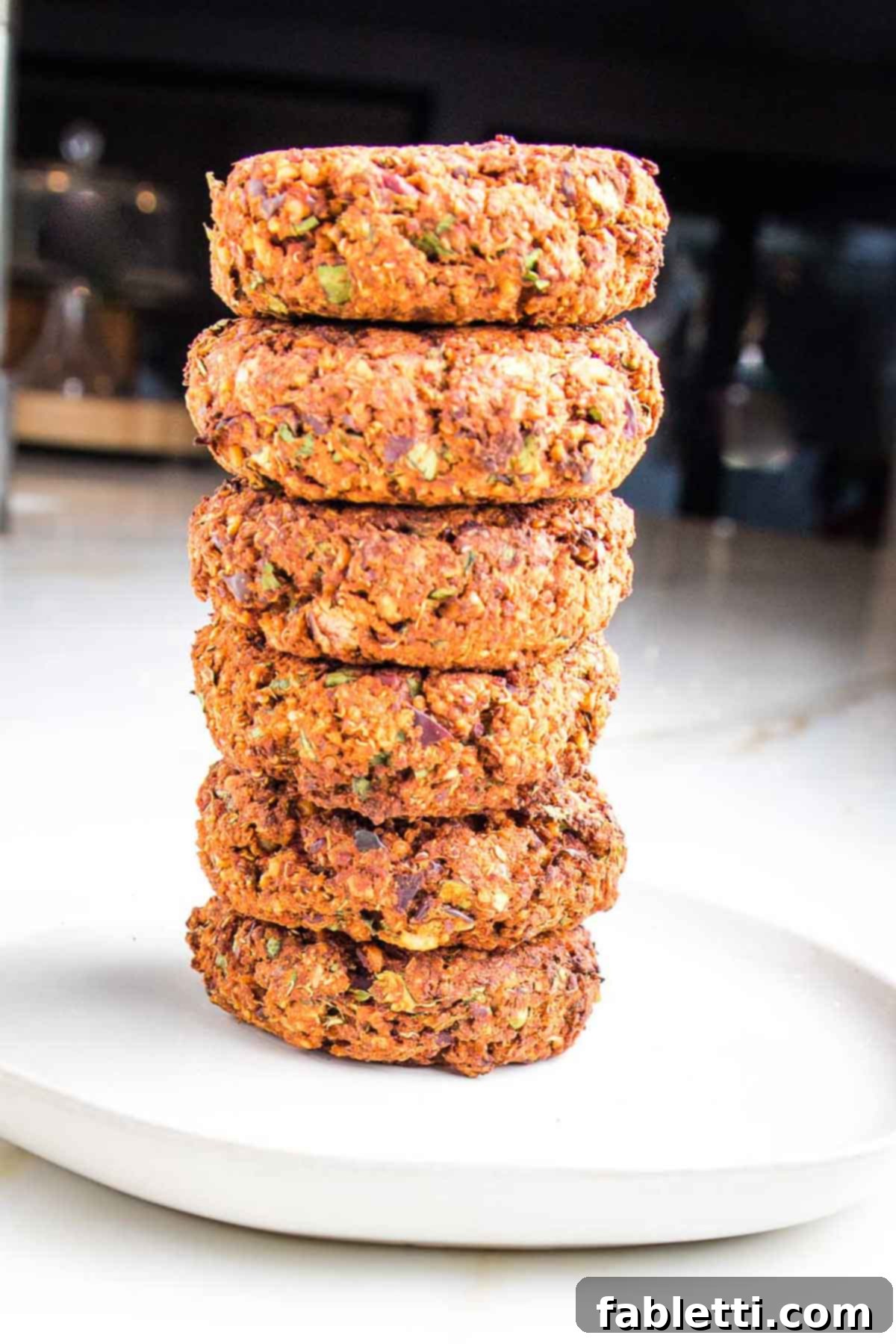 A close-up shot of a single perfectly cooked quinoa veggie burger patty with a rustic texture and golden-brown crust, garnished with a sprig of fresh herbs.