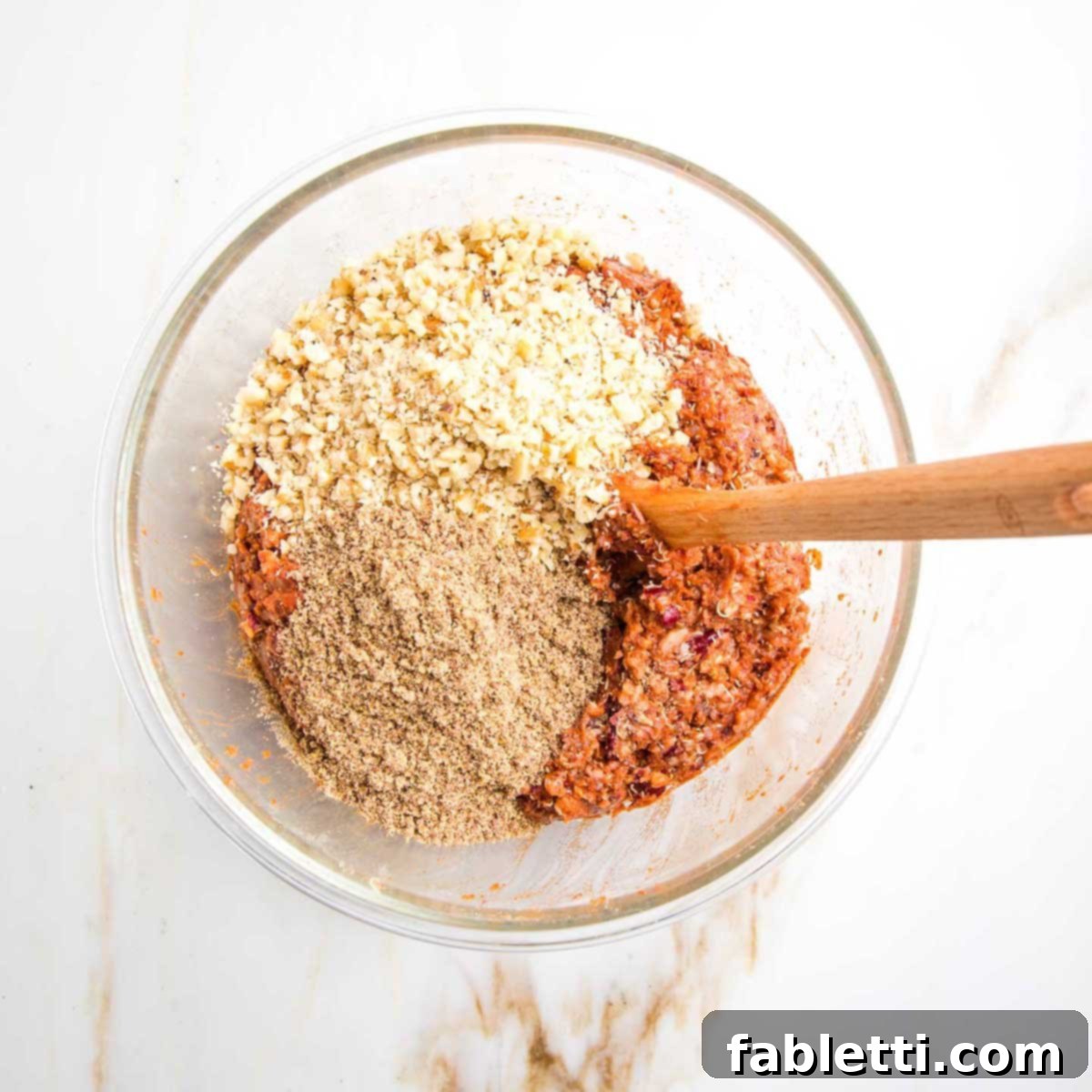 The veggie burger mixture, now enriched with ground flaxseed and finely chopped walnuts, showing a textured, cohesive blend of ingredients.