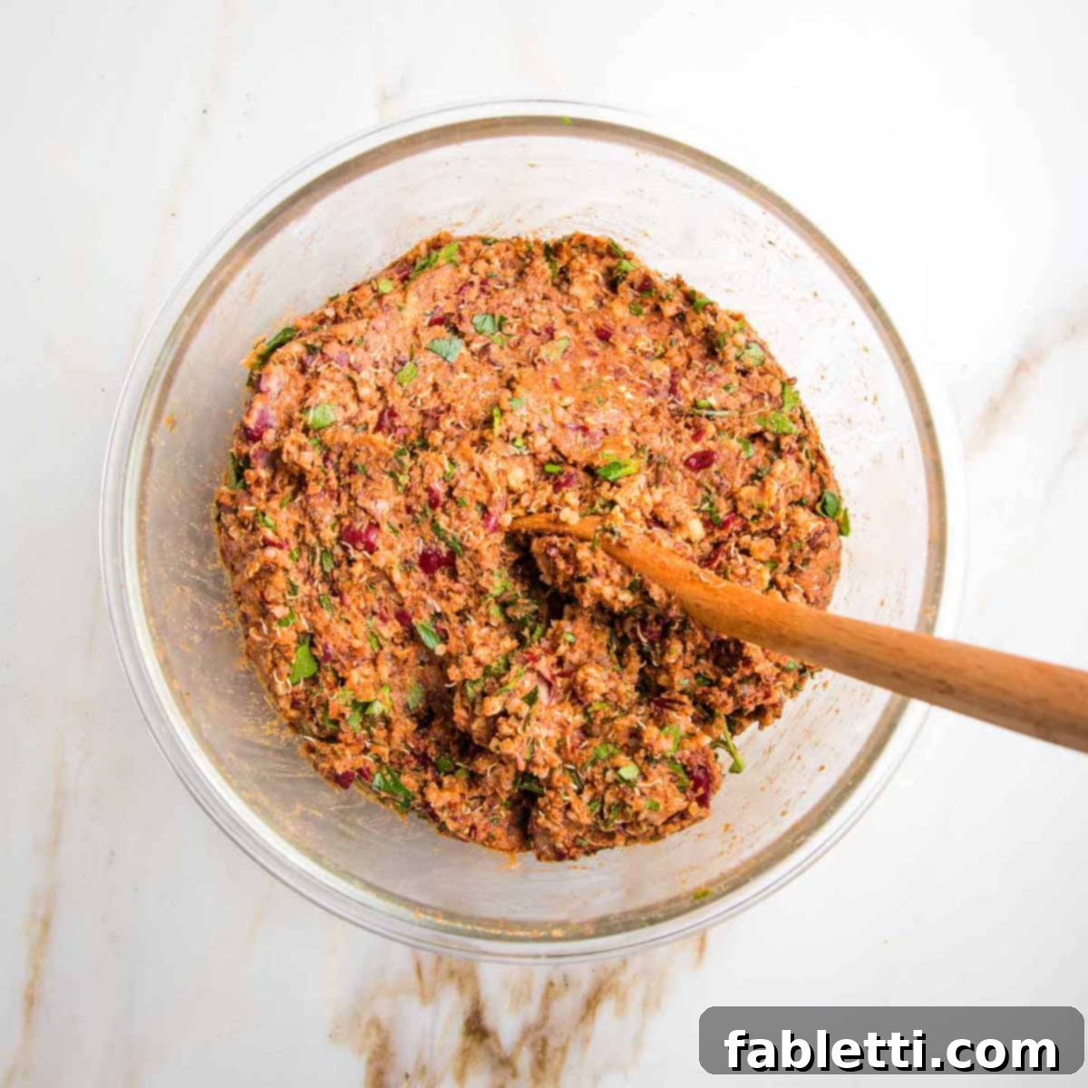 The fully combined veggie burger mixture in a glass bowl, displaying a uniform brownish-red color and a textured consistency, ready for forming into patties.
