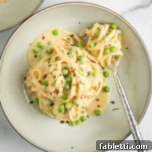 Saucy Fettuccine Alfredo with green peas and crushed red pepper flakes.