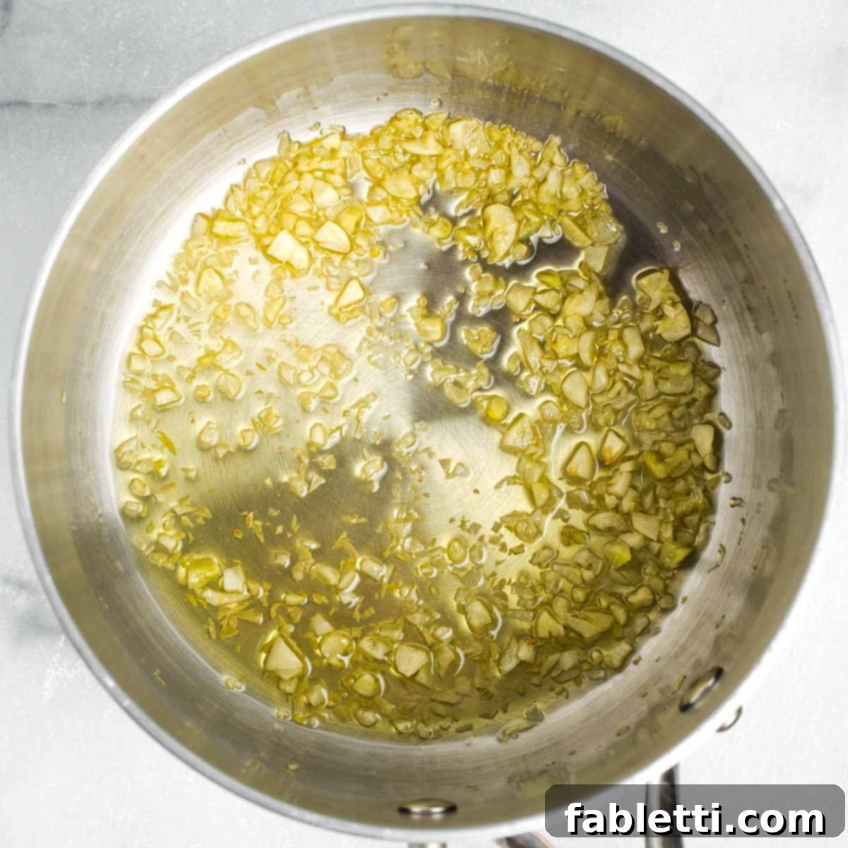 Garlic sautéing in olive oil in a small saucepan.