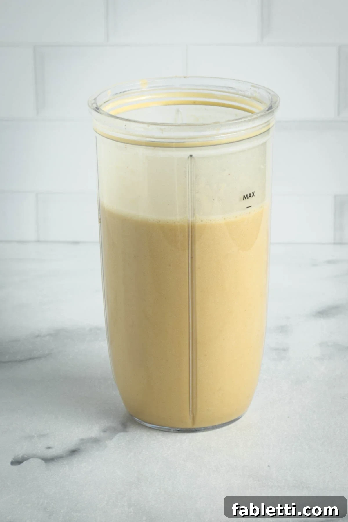 Blender cup filled with the creamy, vegan Alfredo sauce.