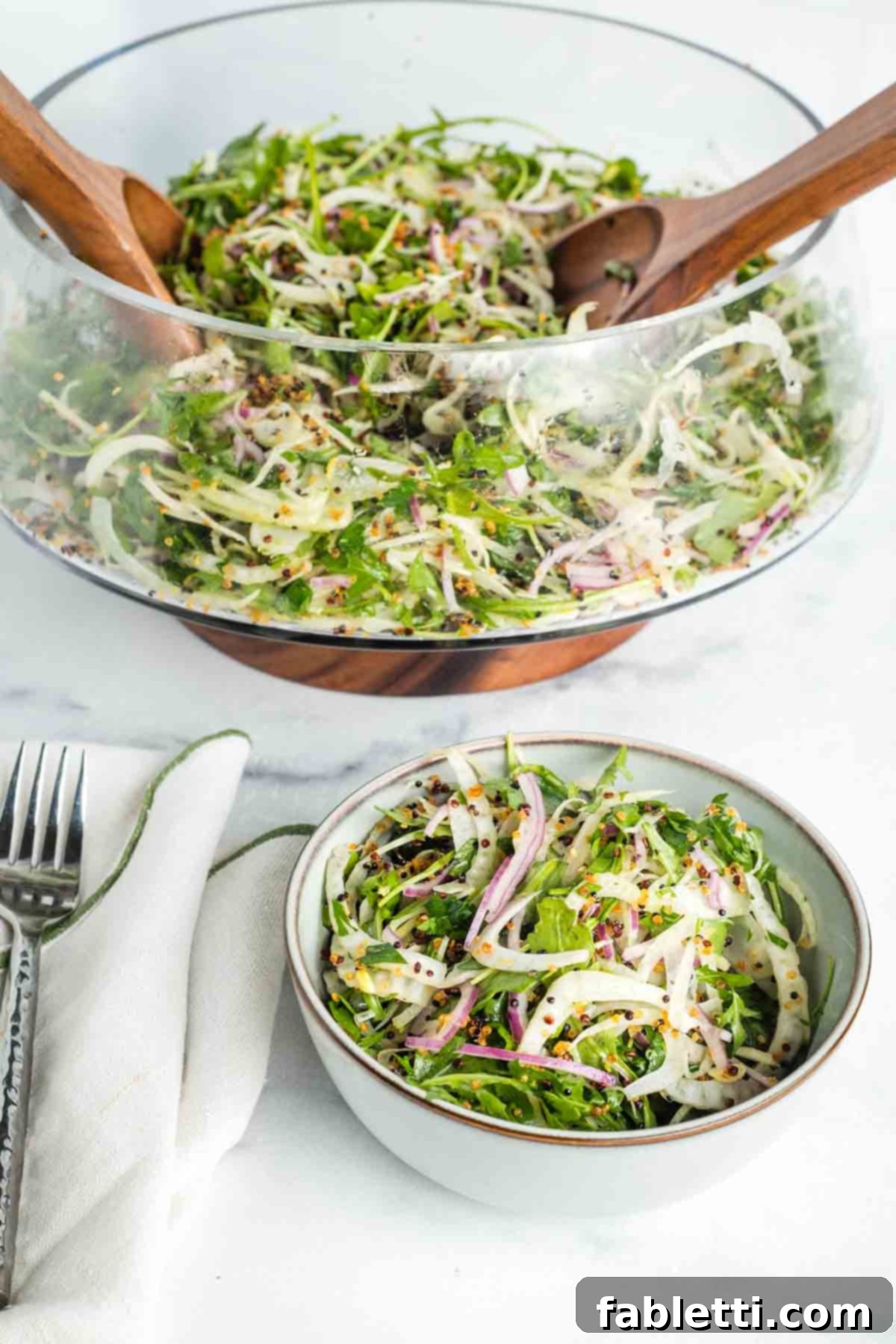 Fennel Arugula Salad with Quinoa Crunch 2 Arugula and shaved fennel salad being scooped into a smaller bowl.