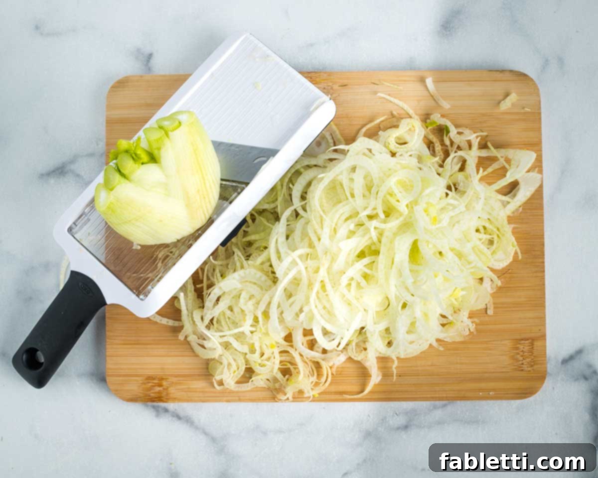 Fennel Arugula Salad with Quinoa Crunch 6 Fennel bulb being thinly sliced with a mandoline.