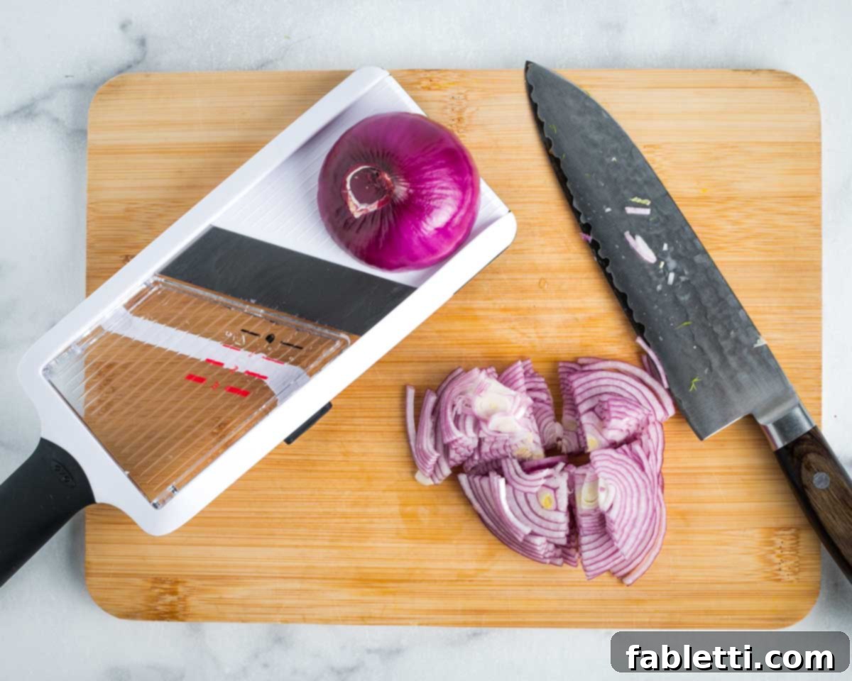 Fennel Arugula Salad with Quinoa Crunch 7 Red onion being thinly sliced with a mandoline.