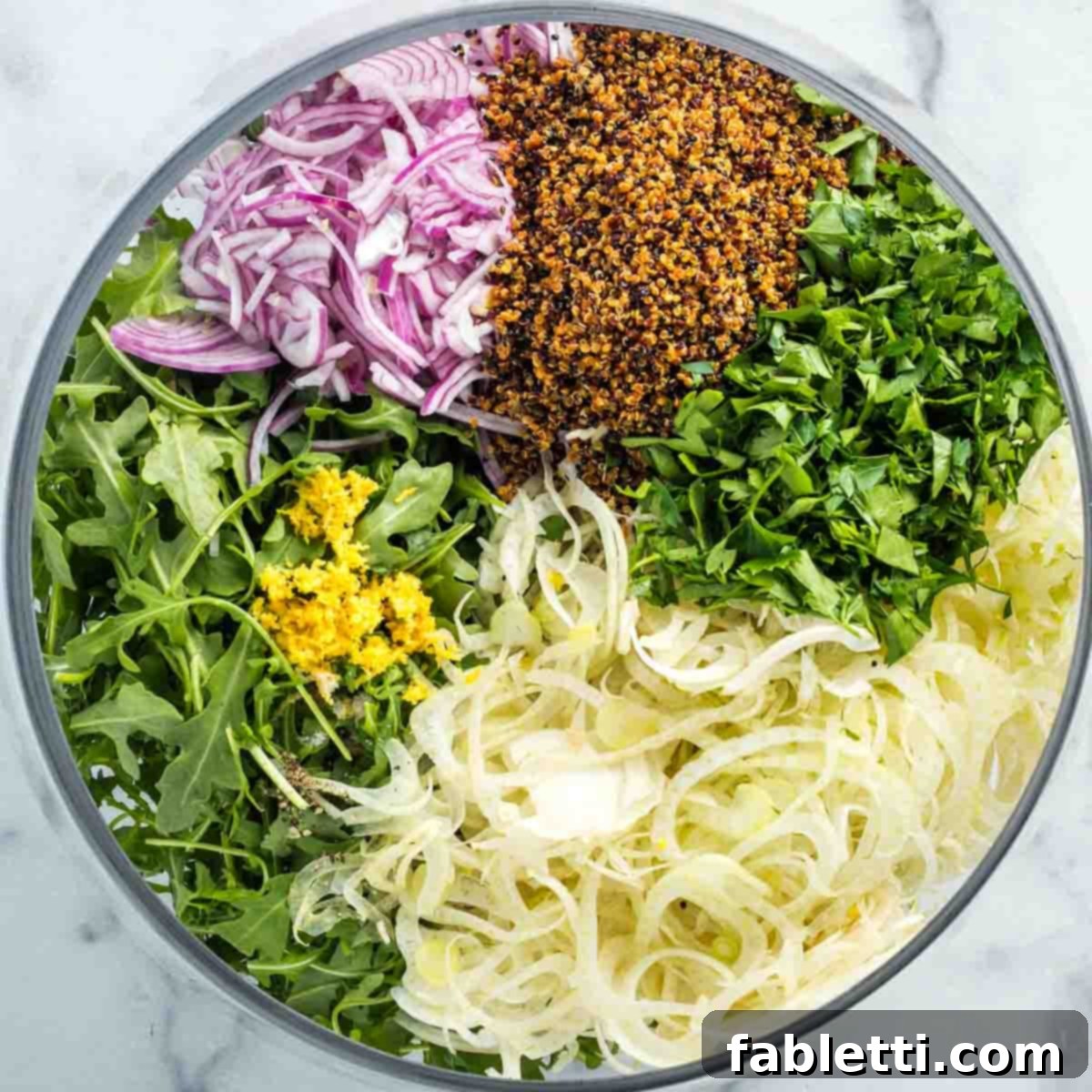 Fennel Arugula Salad with Quinoa Crunch 8 Salad ingredients sectioned in a bowl.