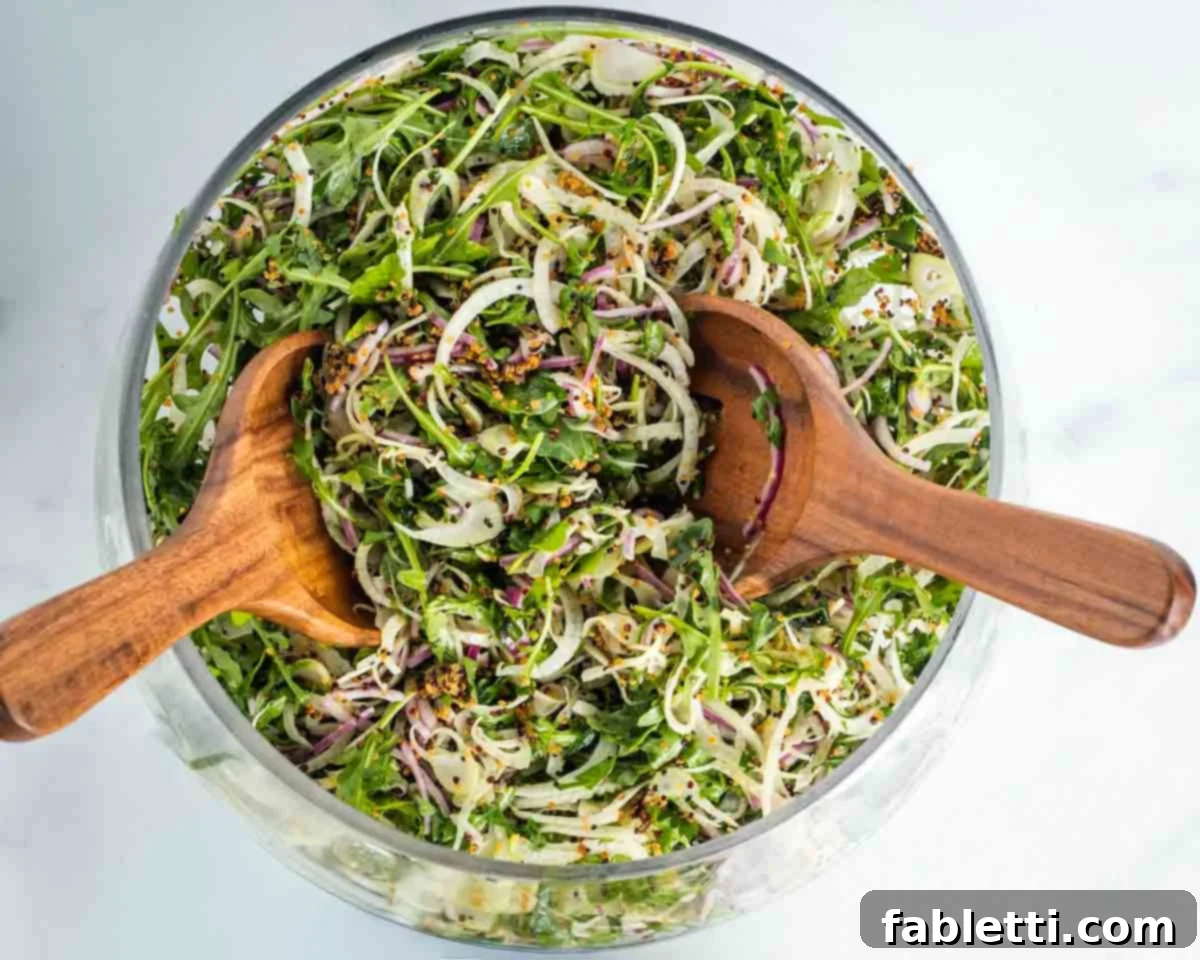 Fennel Arugula Salad with Quinoa Crunch 10 Wooden salad servers tossing a large chopped salad.